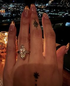 a person's hand with a ring on it and a city in the background