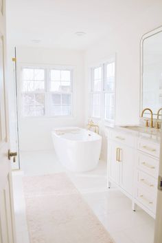 a white bathroom with a large tub and sink