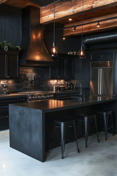 a large kitchen with black cabinets and counter tops, lights hanging from the ceiling over the island