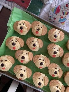 cupcakes with frosting and dogs on them are sitting on a green tray