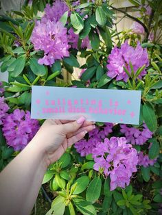 a person holding up a sign with flowers in the background