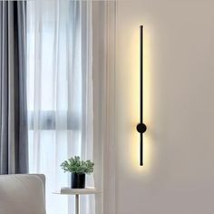 a wall light that is on the side of a wall next to a chair and table