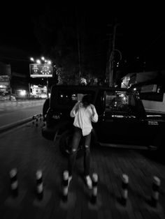 a man standing next to a parked car in the dark