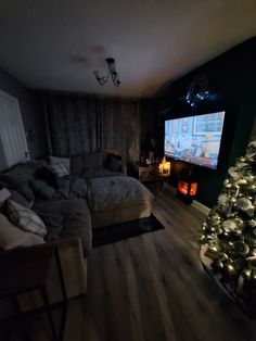 a living room with a christmas tree in the corner and a flat screen tv on