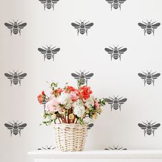 a basket filled with flowers sitting on top of a white table next to a wall