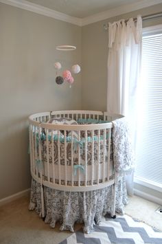 a baby crib in the corner of a room next to a window with curtains