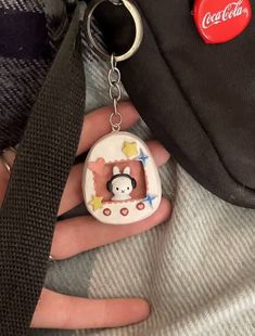 a person holding a coca cola keychain with a monkey on it