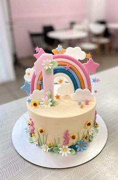 a birthday cake decorated with flowers and rainbows