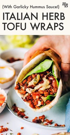 a person holding a pita filled with meat and vegetables on top of a plate