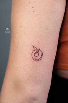 a woman's arm with a small apple tattoo on the left side of her arm