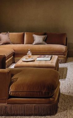 a living room filled with lots of brown couches and pillows on top of each other