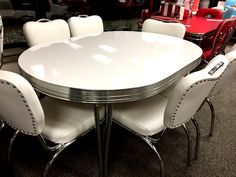 a white table surrounded by chairs in a room with other furniture and accessories on the floor