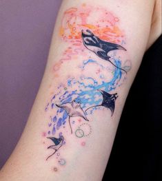 a woman's arm with two dolphins on it and stars in the sky behind her