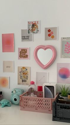 a white desk topped with lots of different types of art and decor on the wall