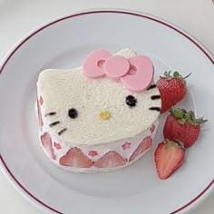 a hello kitty cake on a plate with strawberries