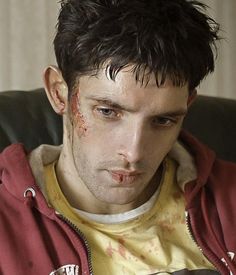 a man with blood all over his face sitting in a chair and looking at the camera