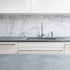 a kitchen with marble counter tops and white cupboards on the wall, along with two sinks