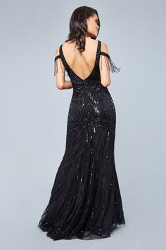 a woman in a black dress with sequins on the shoulders and back, looking over her shoulder