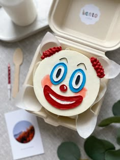 a close up of a cake in a box with a clown face on the front