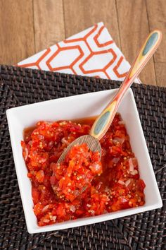 a white bowl filled with red sauce and two wooden spoons on top of it