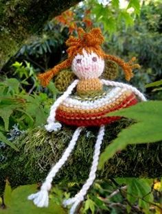 a crocheted doll sitting on top of a tree branch