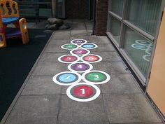 a sidewalk with numbers painted on it next to a child's chair and window