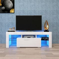 an entertainment center with a flat screen tv mounted on it's side, in front of a blue wall