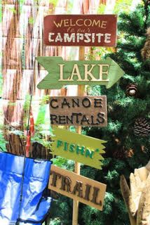 wooden signs pointing in different directions near a christmas tree with pine cones and other decorations