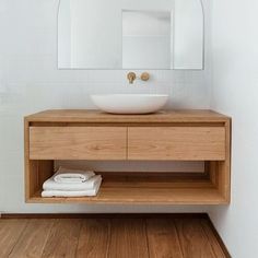 a bathroom with a sink, mirror and wooden flooring in it's center