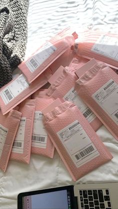 a pile of pink tickets sitting on top of a bed next to a laptop computer