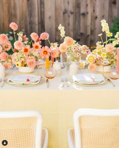 the table is set with flowers in vases and place settings for two people to sit at