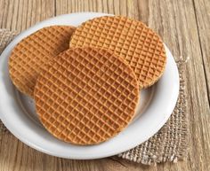 three waffles on a white plate with burlocked cloth next to them