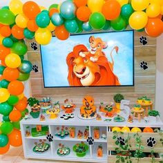 a lion themed birthday party with balloons and decorations on the wall, including a large screen