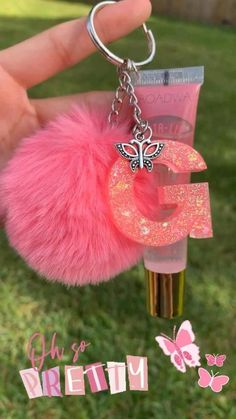 a pink keychain with the letter g on it and a butterfly charm attached to it