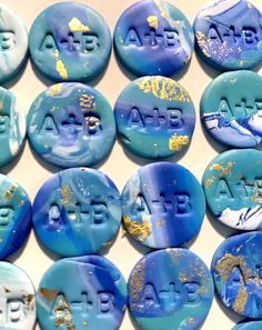 some blue and white buttons with gold paint on them that say atee above the letters