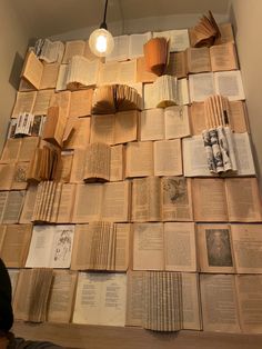 many books are stacked on top of each other in front of a light fixture that is hanging from the ceiling