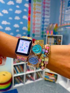 a woman's arm with several bracelets on it and an apple watch displaying the time