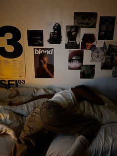 a man laying on top of a bed under posters