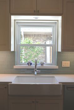 a white kitchen sink sitting under a window