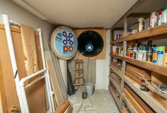 the inside of a storage room with various items on shelves and tools hanging from the wall