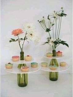 three vases with flowers and cupcakes on them