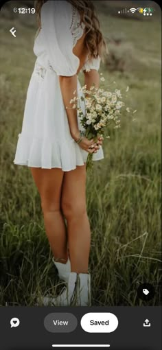 a woman standing in tall grass holding a bouquet of flowers and looking at the sky