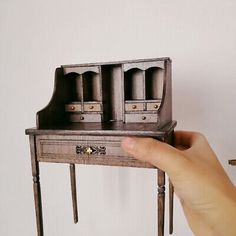 a hand holding a miniature desk with two drawers