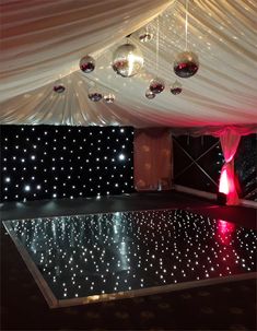 a dance floor with disco balls hanging from the ceiling and white drapes covering it