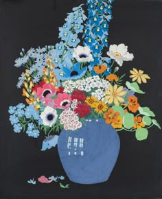 a blue vase filled with lots of colorful flowers on top of a wooden table next to a black wall