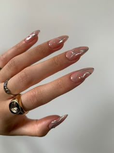 a woman's hand with long, shiny nails and gold rings on her fingers