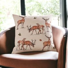 a deer pillow sitting on top of a brown chair in front of a large window