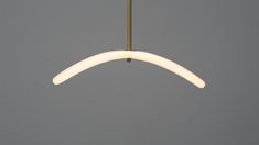 a white light hanging from a brass colored ceiling fixture against a gray background with no one in it