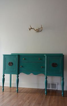 two green dressers sitting on top of a hard wood floor next to a white wall