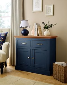 a living room with blue furniture and pictures on the wall above it, along with a white chair